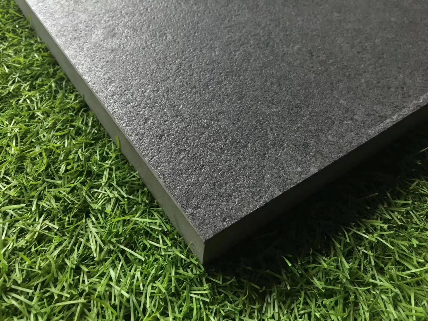 close-up of outdoor porcelain paver in natural stone texture with a ruler showing 20mm thickness